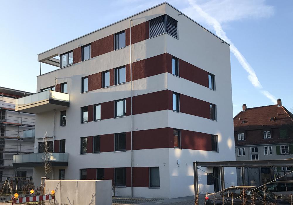 Kräftig rote Putzstreifen nehmen die Sandsteintöne der Umgebung auf.